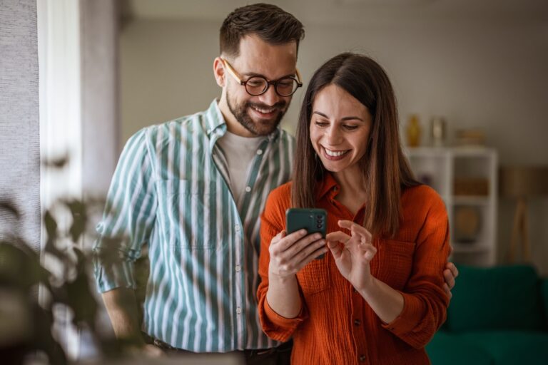 Cheerful,Young,Couple,Lounging,At,Home,,Smiling,As,They,Browse