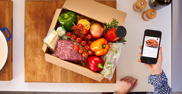 Kochbox mit frischen Zutaten und Rezeptkarte auf einer Küchenarbeitsfläche