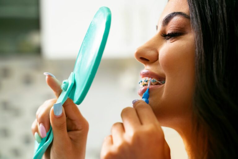 Pretty,Satisfied,Young,Woman,Holding,Mirror,And,Interdental,Brush,,Dental